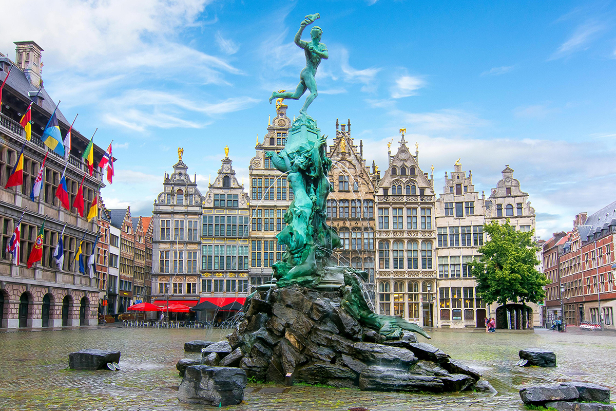 a statue of a person holding a torch in a fountain in a city